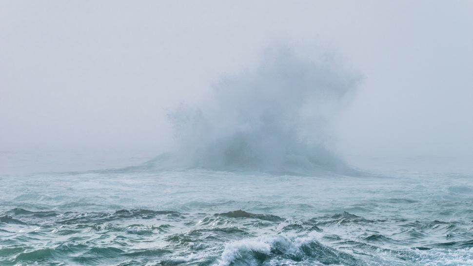 Free Image of Ocean waves crashing with mist in a stark seascape. 