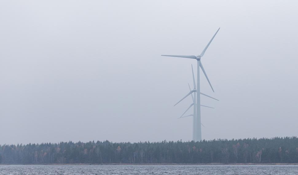 Free Image of Towering wind turbines against a foggy forest landscape 