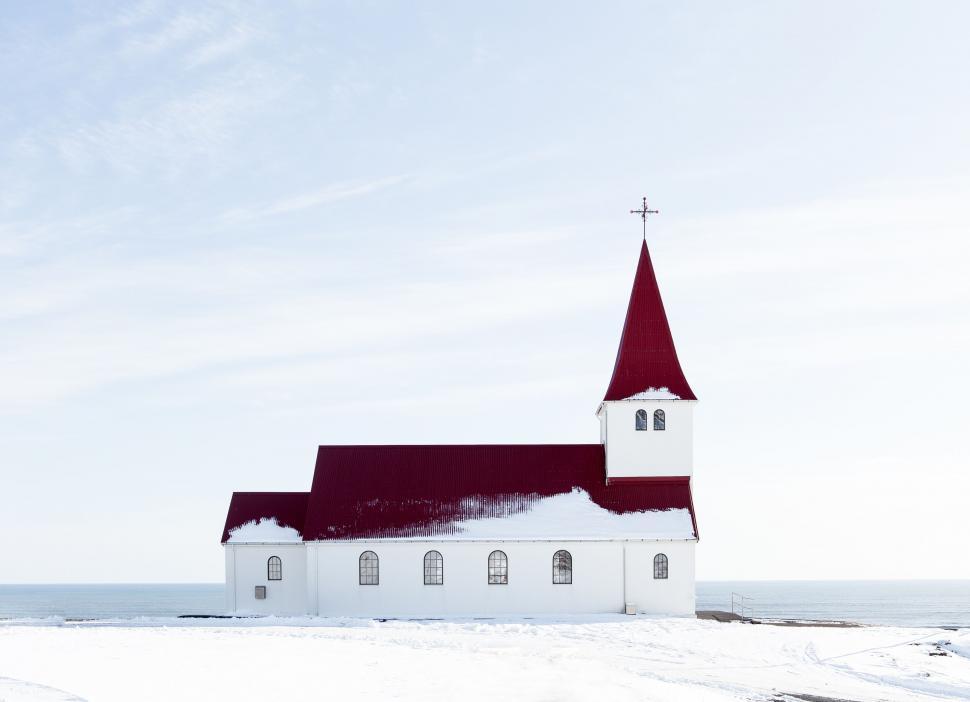Free Image of Snow-covered church with red roof by the ocean 