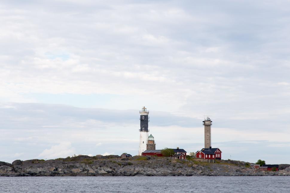 Free Image of Isolated lighthouse on rocky terrain by the calm sea 