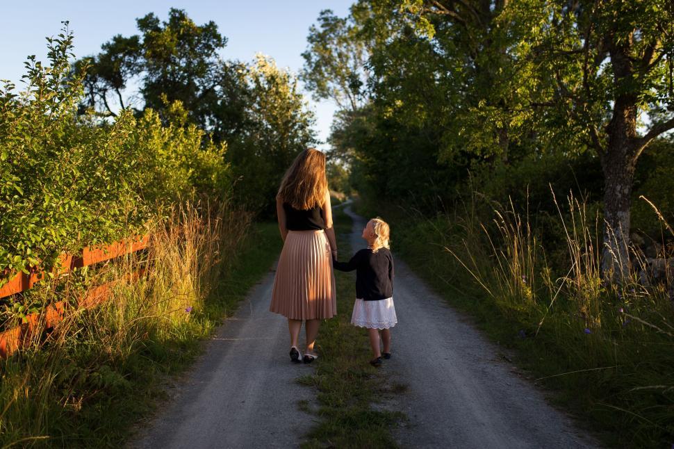 Free Image of Mother and daughter walking hand in hand at sunset 