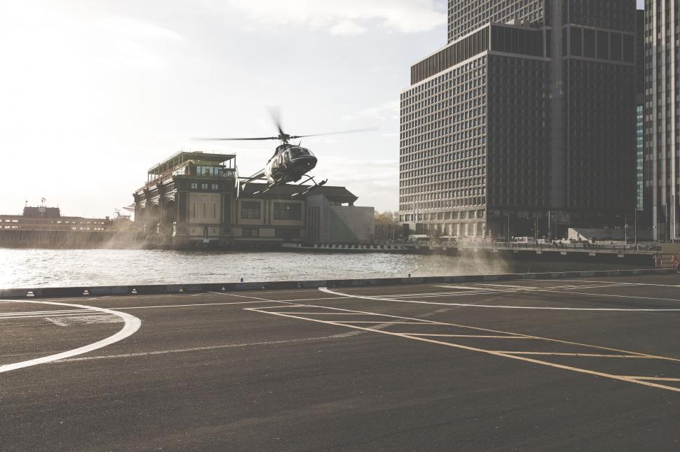 Free Image of Helicopter landing by a river in a modern cityscape 