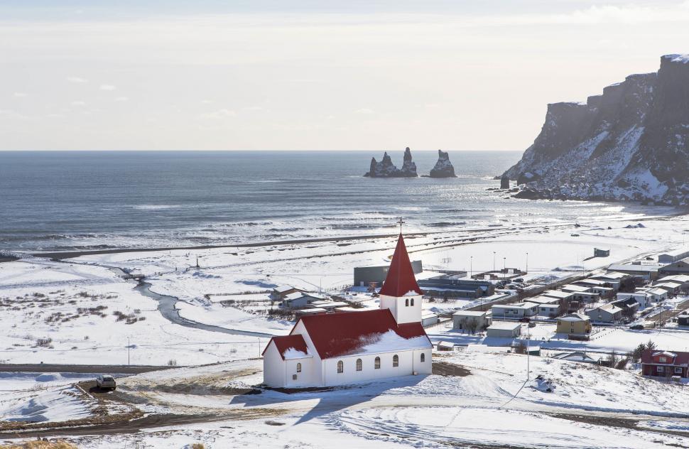 Free Image of Snow-covered church facing the serene ocean backdrop 