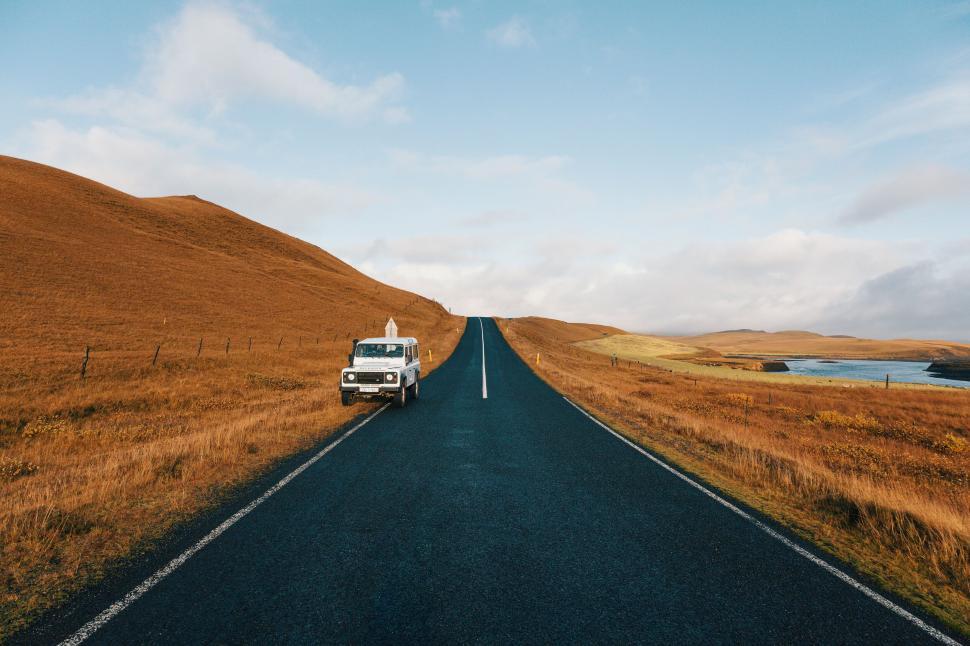 Free Image of Empty scenic road with car under vast blue sky scenery 