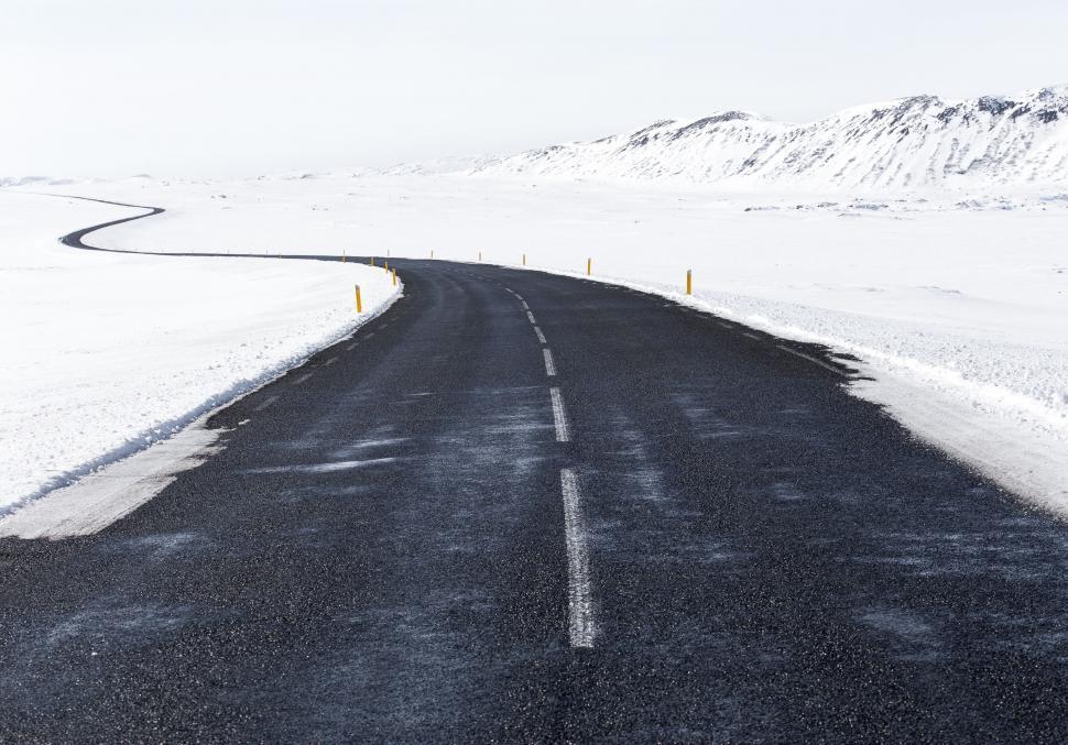 Free Image of Long empty road cutting through snow-covered landscape 