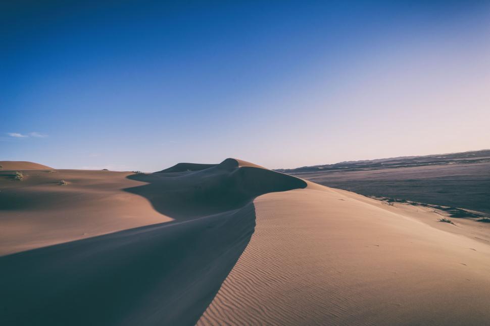 Free Image of Expansive desert dunes under a clear, bright blue sky. 