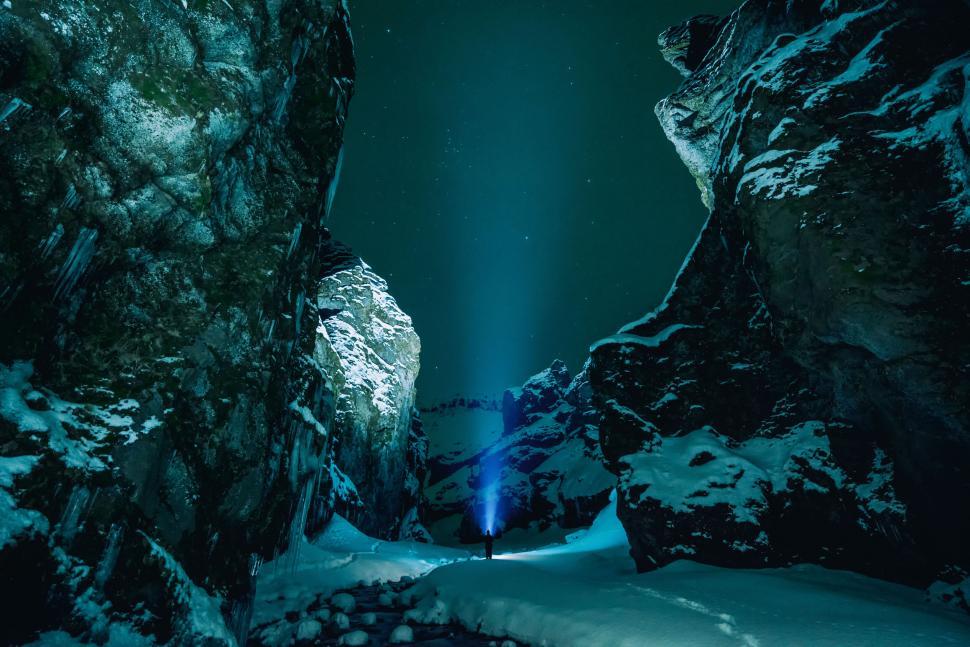 Free Image of Person holding light in dark snow-covered canyon 