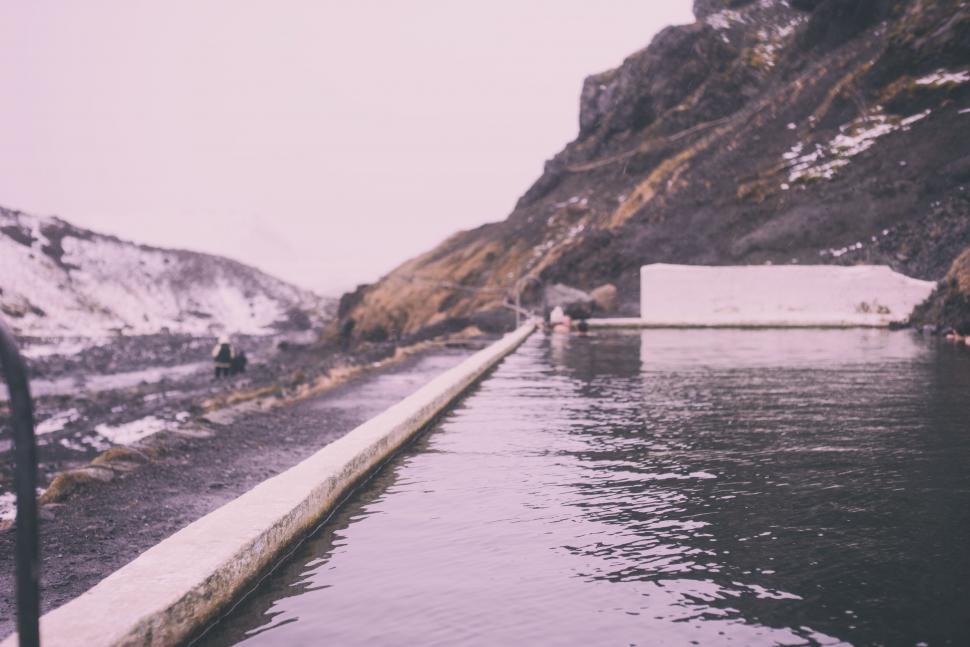 Free Image of Natural hot spring pool surrounded by rocky, misty terrain. 