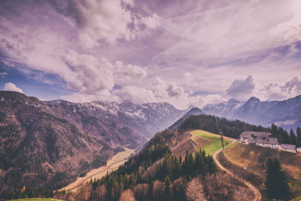 Free Image of Sprawling mountain valley under partially cloudy blue sky. 