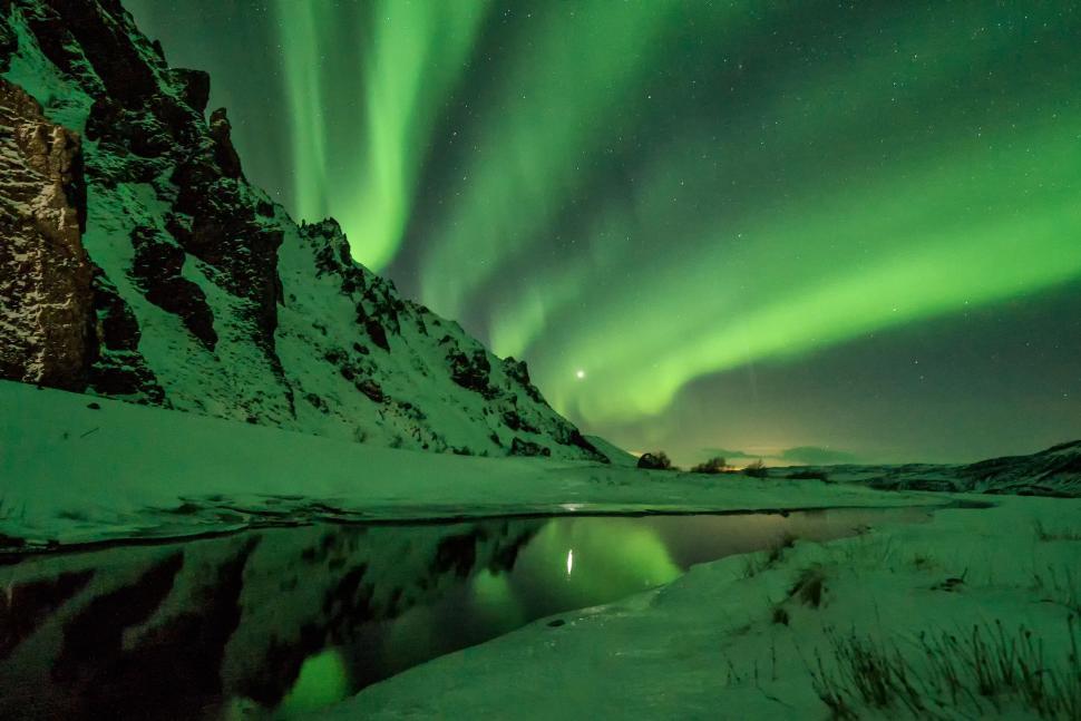 Free Image of Northern lights dance over a snowy mountain landscape 