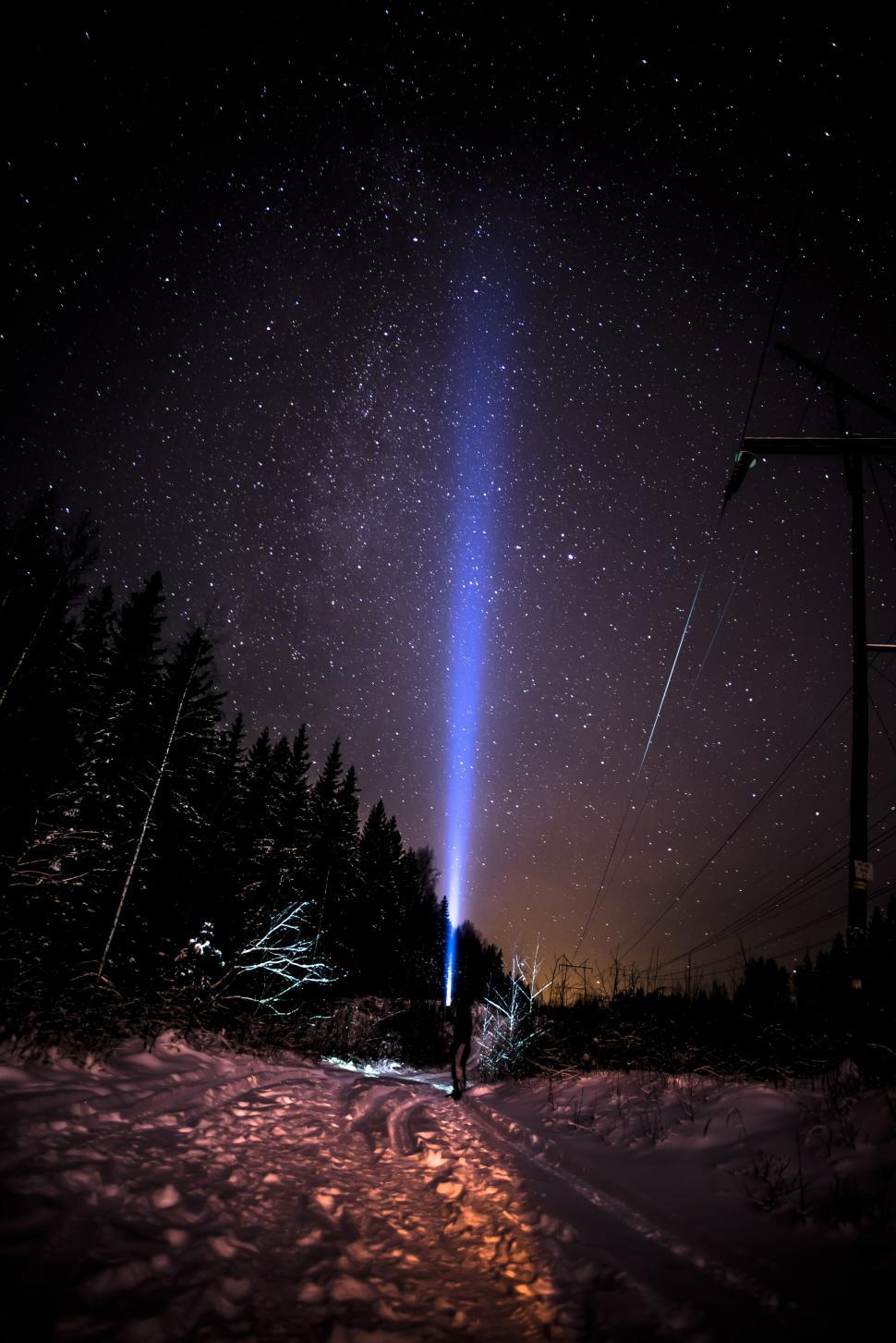 Free Image of Mystical figure shines light into the starry night sky 