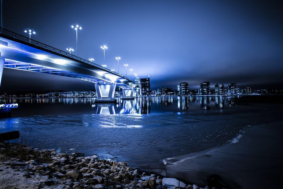 Free Image of Modern bridge illuminated in blue over a waterfront cityscape 