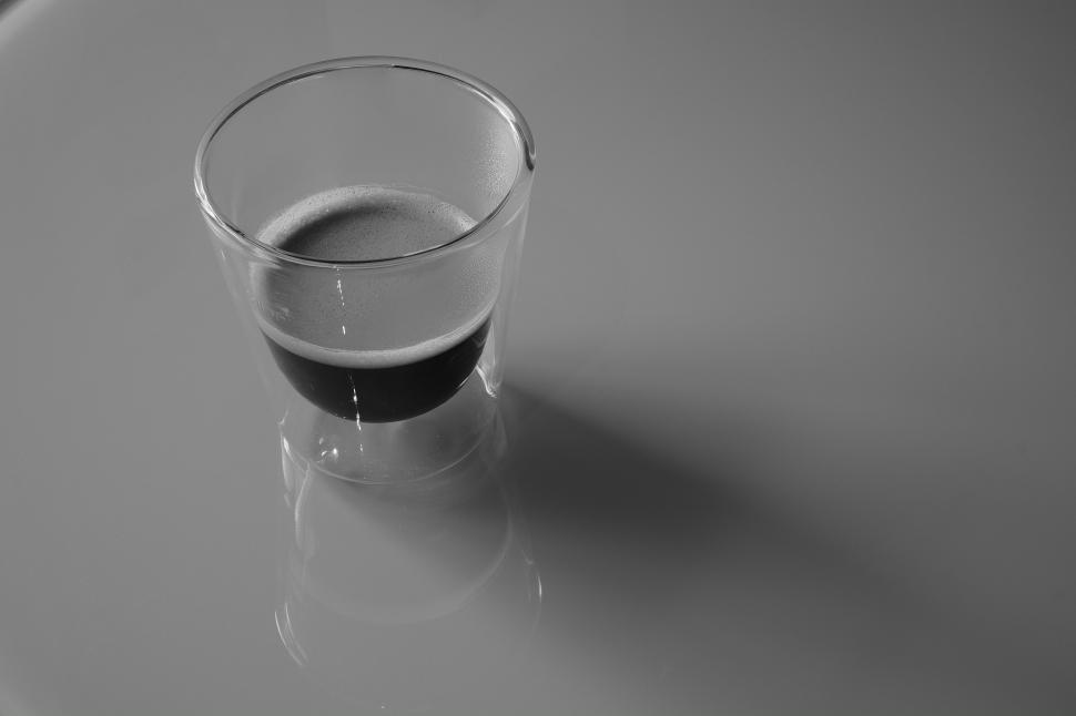 Free Image of Minimalist glass cup of espresso casting long shadow. 