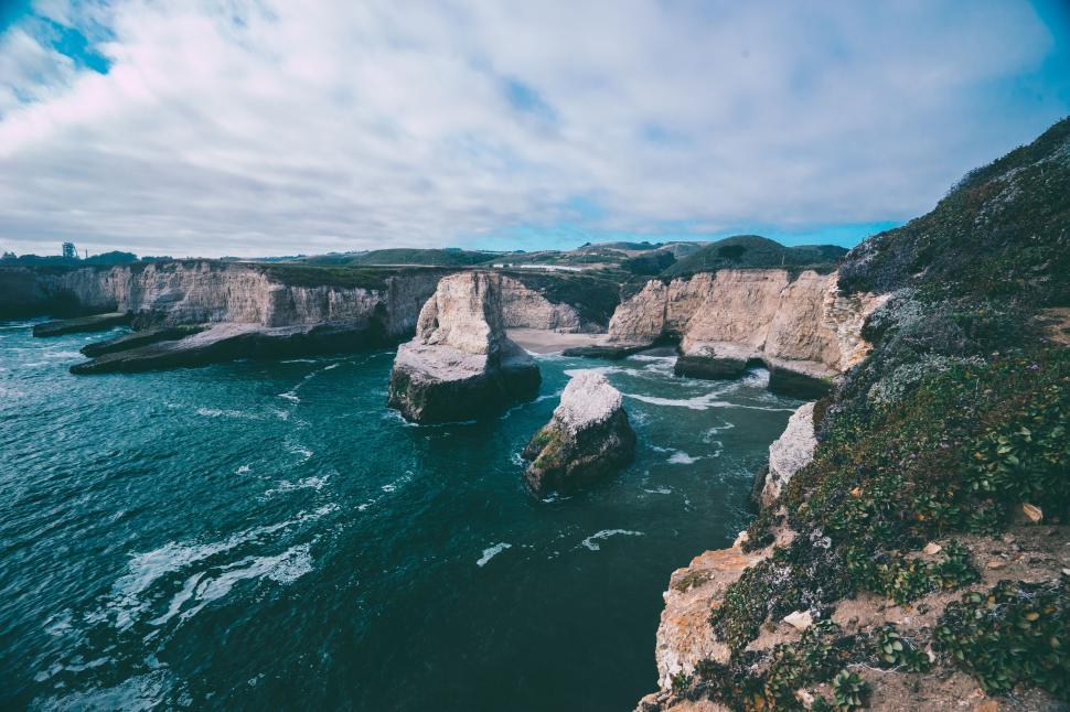 Free Image of Rugged cliffs and rocks overlooking a turbulent blue sea 