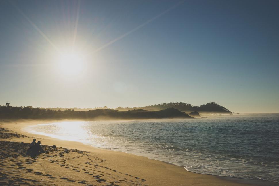 Free Image of Calm sunny beach with clear sky and distant hills. 