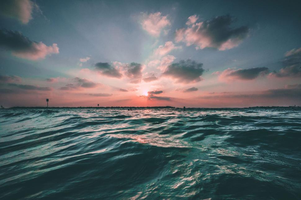Free Image of Ocean waves rolling towards shore under sunset sky. 