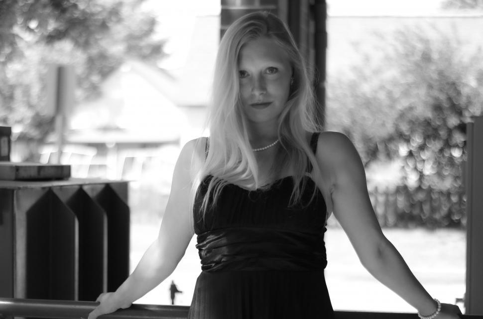 Free Image of Woman in black dress leaning on a railing 