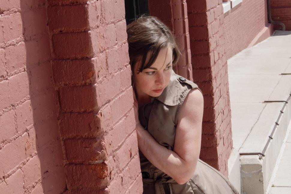 Free Image of Person standing beside a brick wall in the sunlight. 