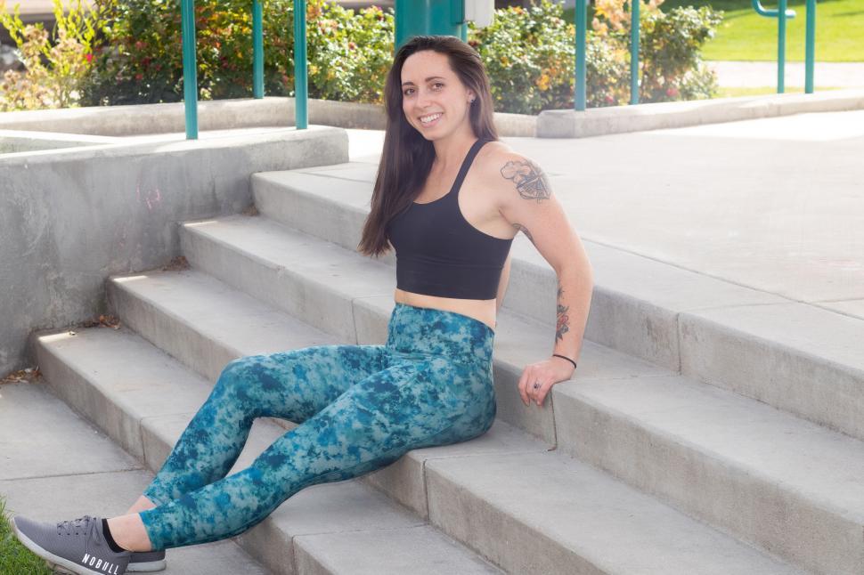 Free Image of Woman in workout attire sitting on outdoor steps smiling 