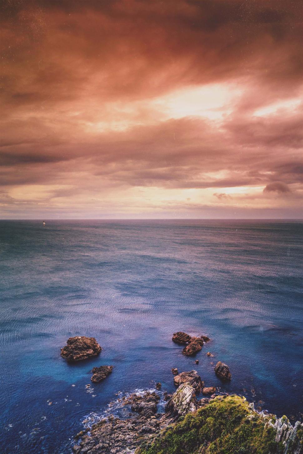 Free Image of Moody ocean scene with dramatic clouds at sunset. 