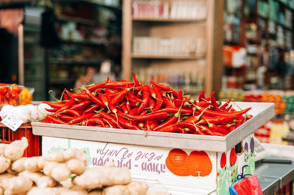 Free Image of Bright red chili peppers stacked in a market stand. 
