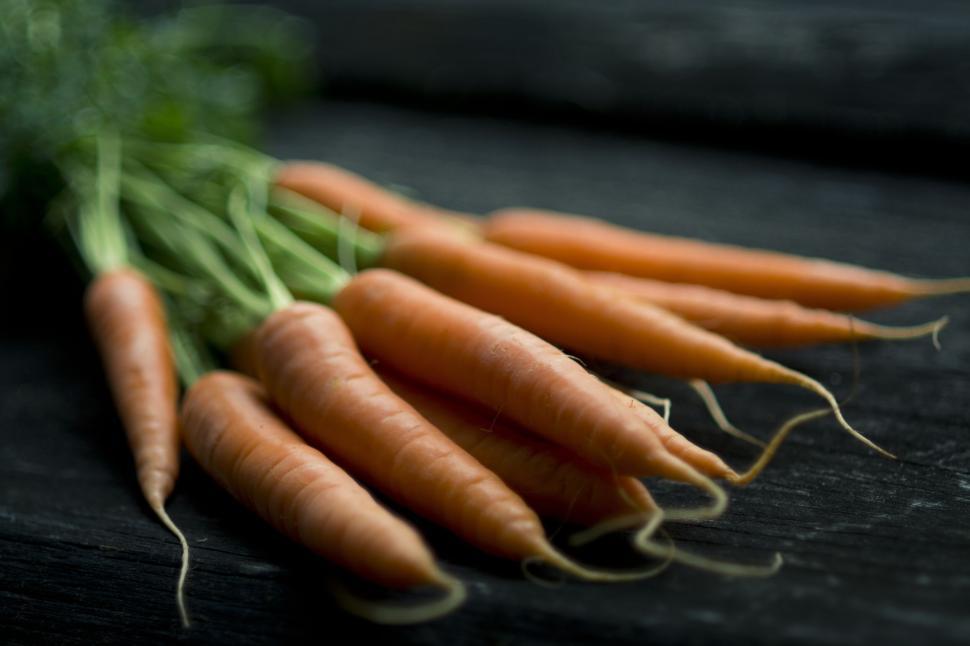 Free Image of Bunch of fresh carrots on a dark wooden surface 