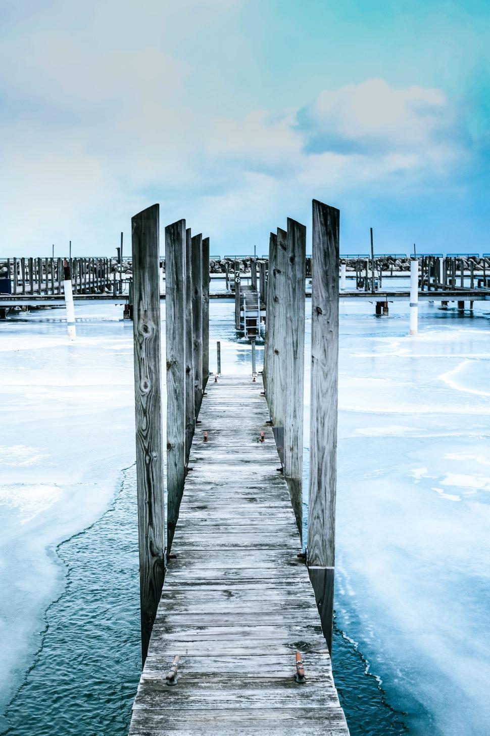 Free Image of Wooden pier extending over frozen lake into horizon. 