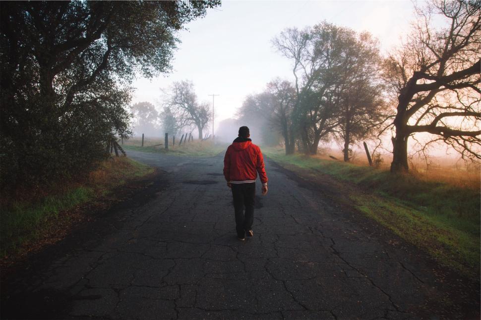 Free Image of Person in red jacket walking down misty deserted road 