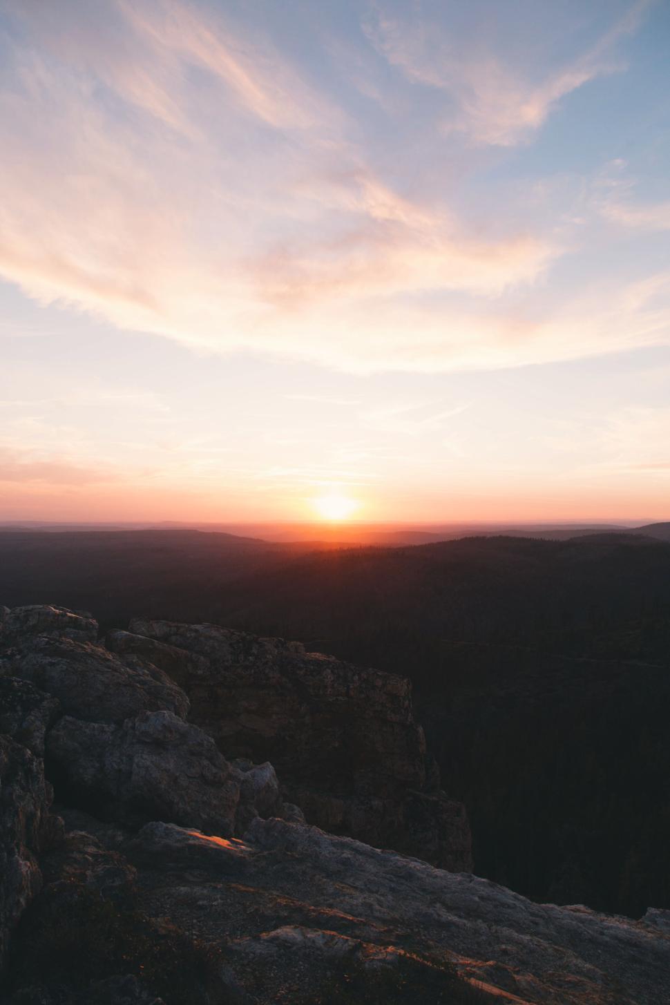 Free Image of Sun setting behind distant hills under colorful sky 