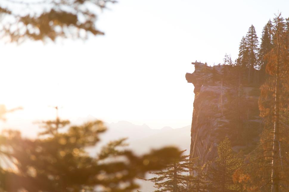 Free Image of Cliff edge subtly lit with morning light and trees 