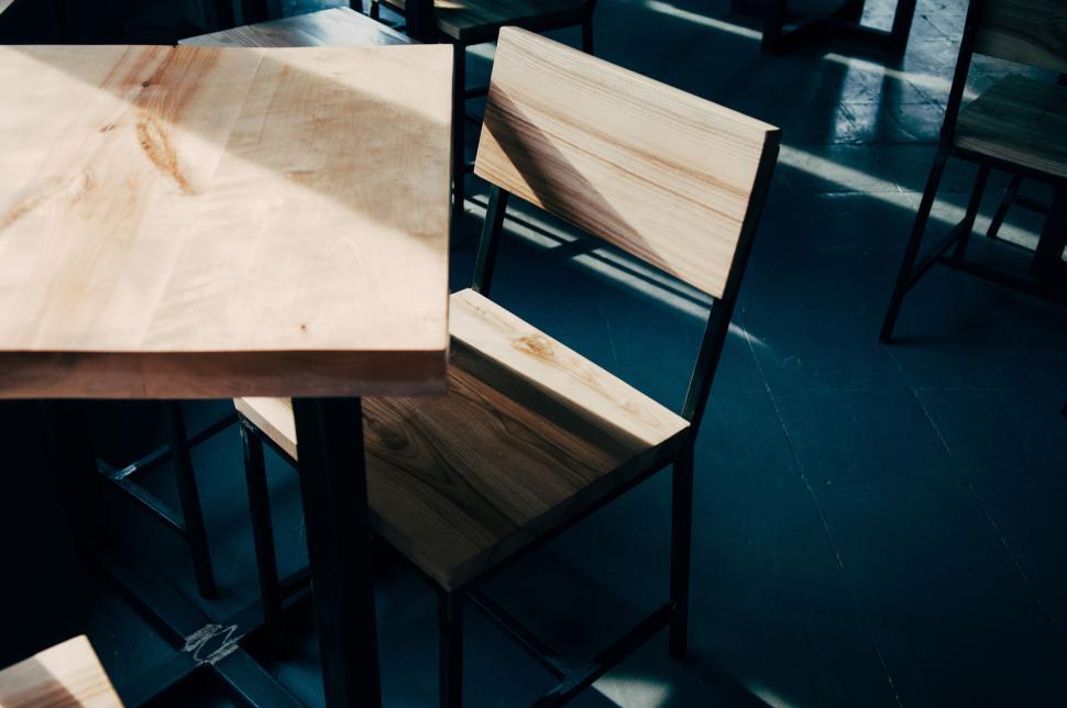 Free Image of Wooden chair and table set bathed in sunlight in caf?. 