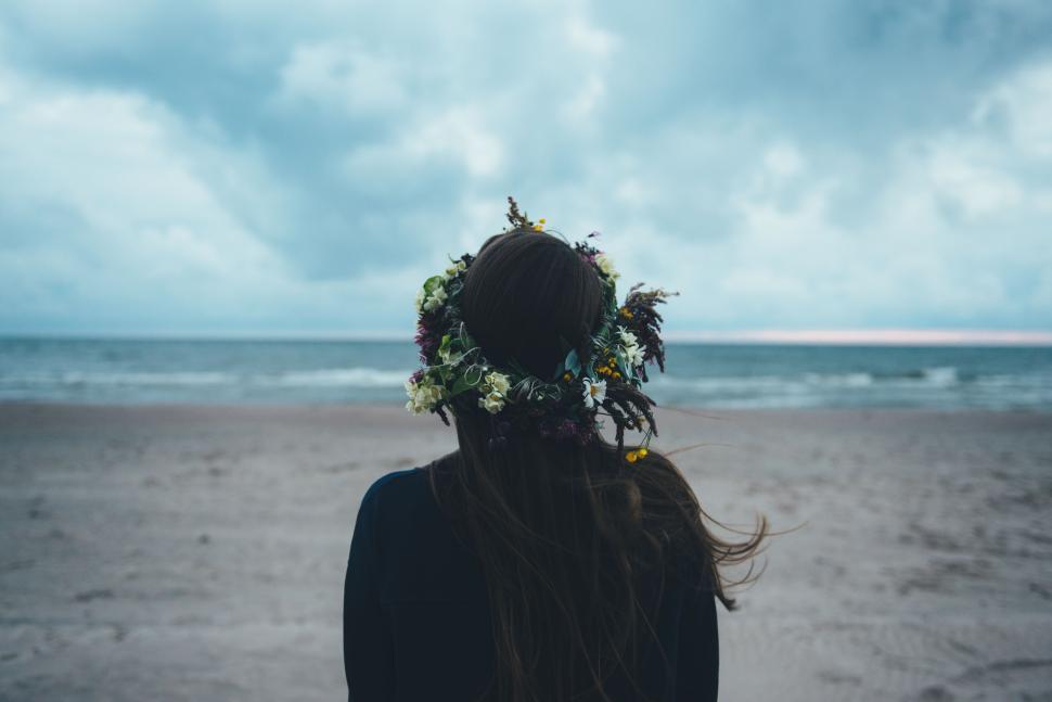 Free Image of Person with floral crown enjoying a tranquil beach scene. 