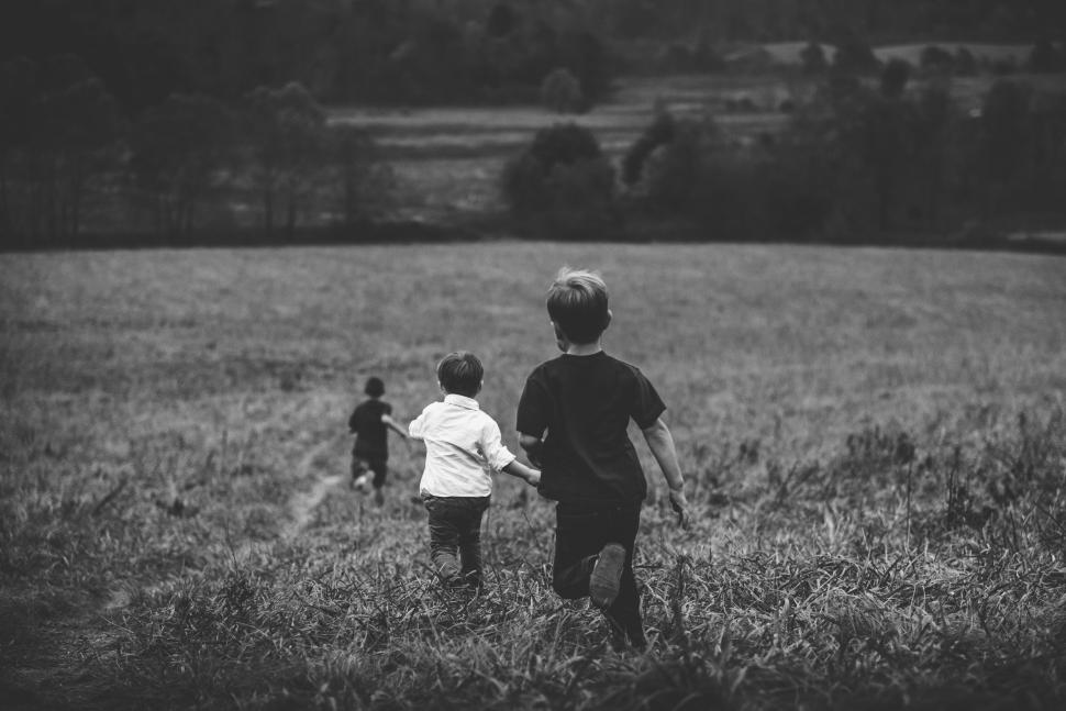 Free Image of Children running down a grassy hill into the distance. 