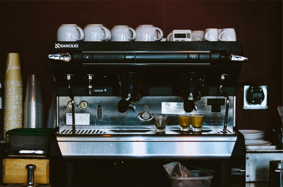 Free Image of Close-up of a coffee machine with cups on top shelf. 