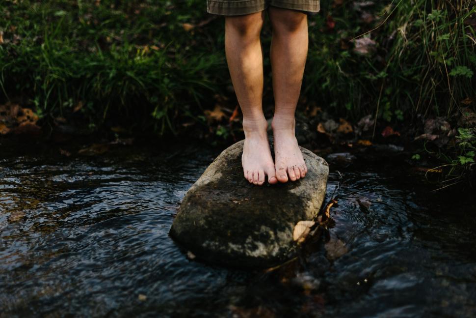 Free Image of Bare feet on rock in gently flowing stream 