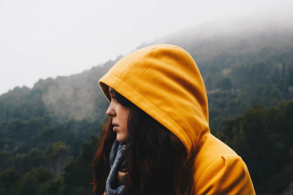 Free Image of Person in yellow hoodie with scenic mountain background. 