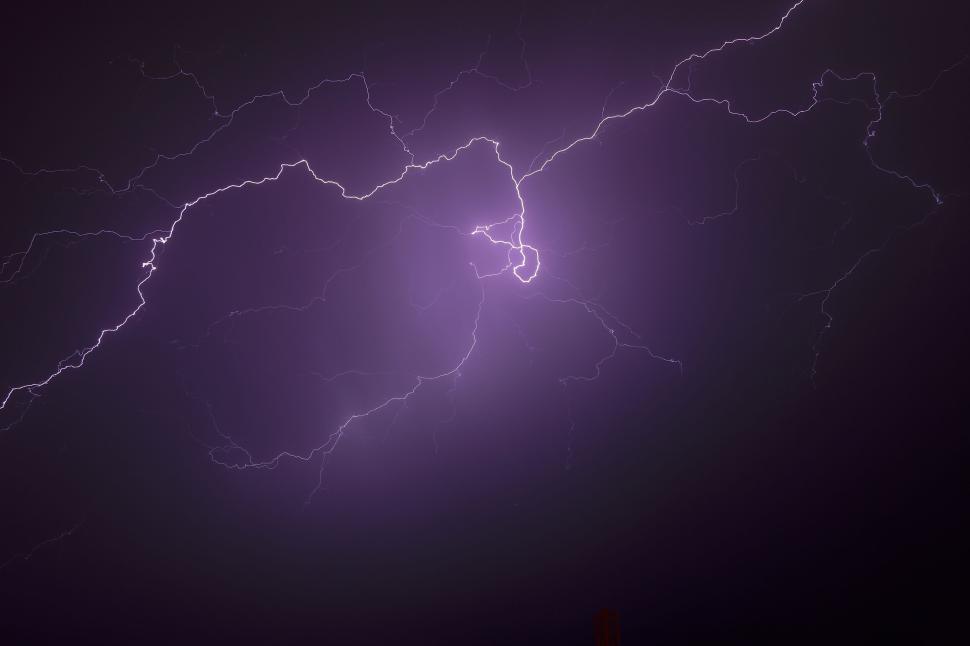 Free Image of Purple lightning bolt striking across the dark night sky. 