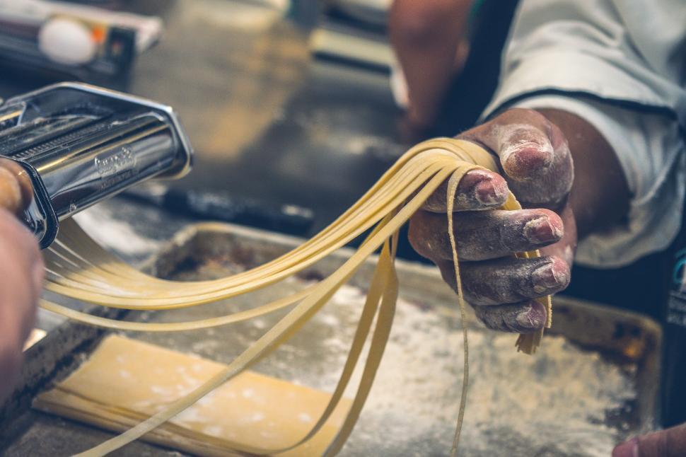 Free Image of Person making pasta by hand using a pasta machine. 