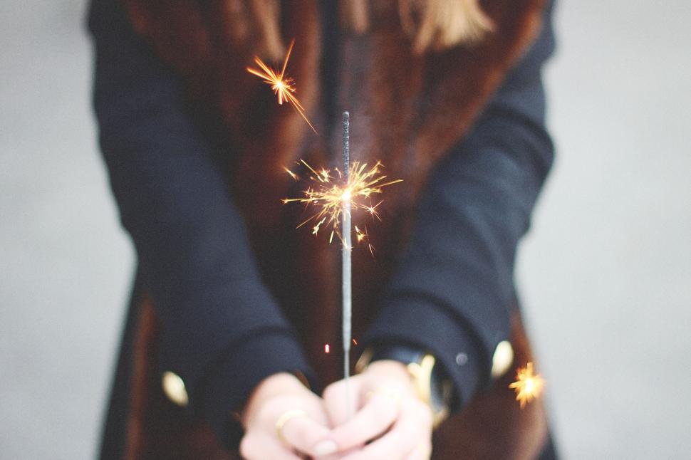 Free Image of Person holding a lit sparkler against a blurred background. 