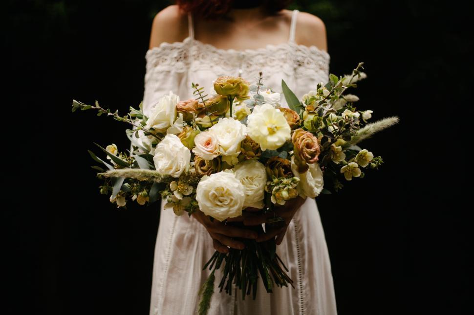 Free Image of Bride holding bouquet of flowers in the nature 