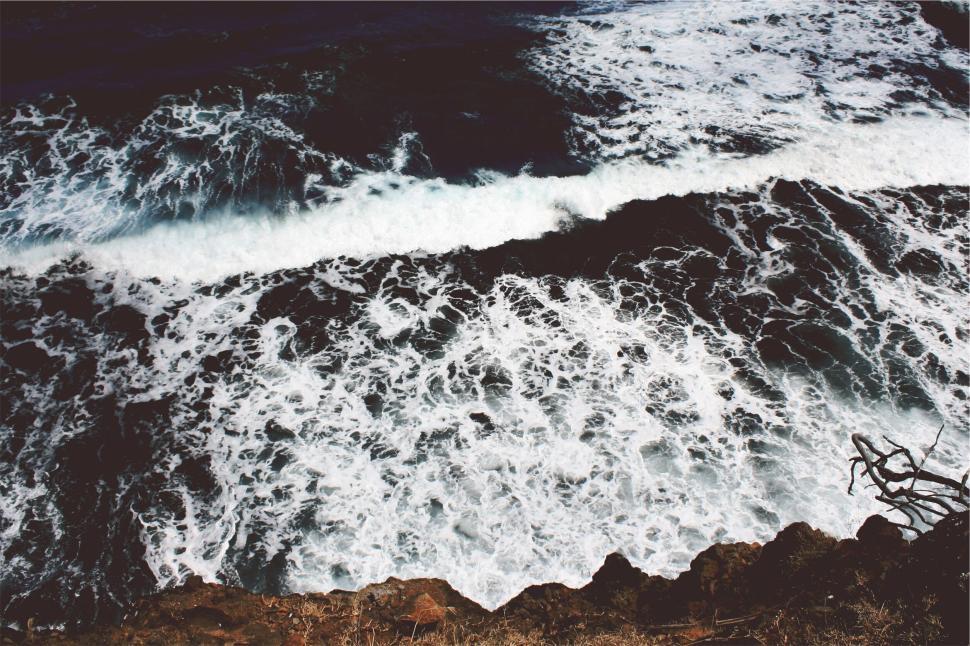 Free Image of Waves crashing against rocky shoreline with foamy surf 