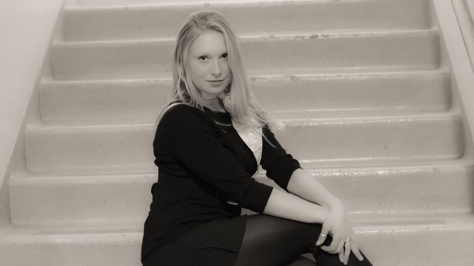 Free Image of Black and white photo of woman sitting on stairs smiling 