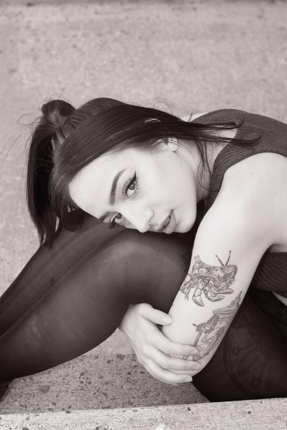 Free Image of Black and white image of woman sitting with tattoos. 