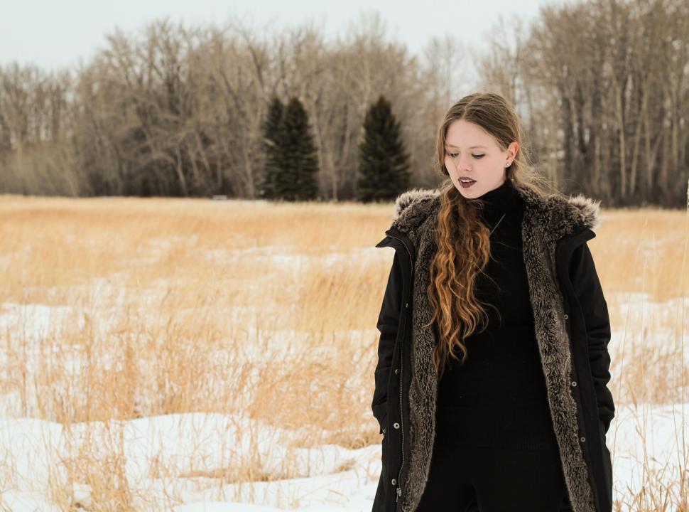 Free Image of Woman in black winter coat standing in snowy field 
