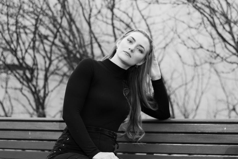 Free Image of Reflective woman in black turtleneck seated on bench. 