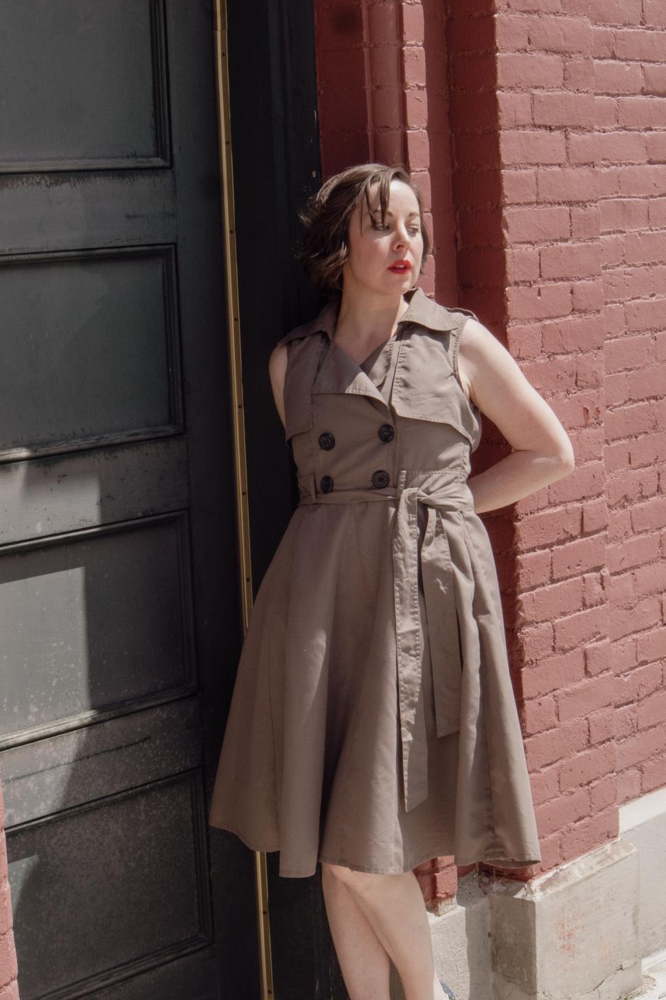 Free Image of Elegant woman in sleeveless dress poses dreamily outside. 