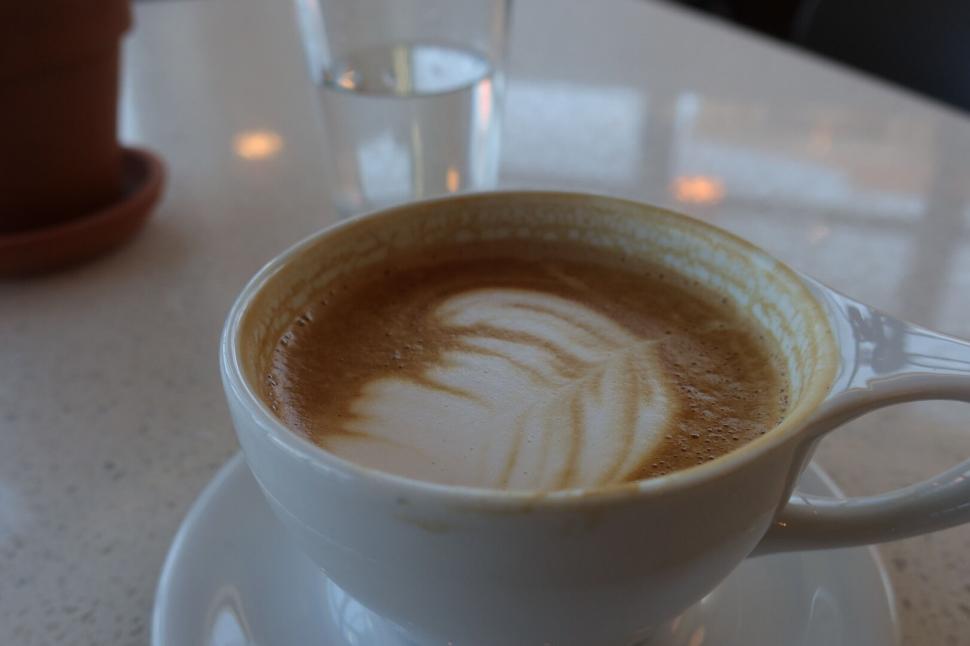 Free Image of Cup of coffee with latte art on white saucer on table. 