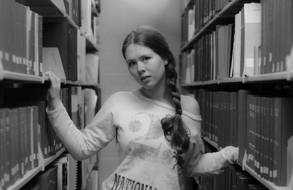 Free Image of Young woman in library aisle wearing casual long sleeve 