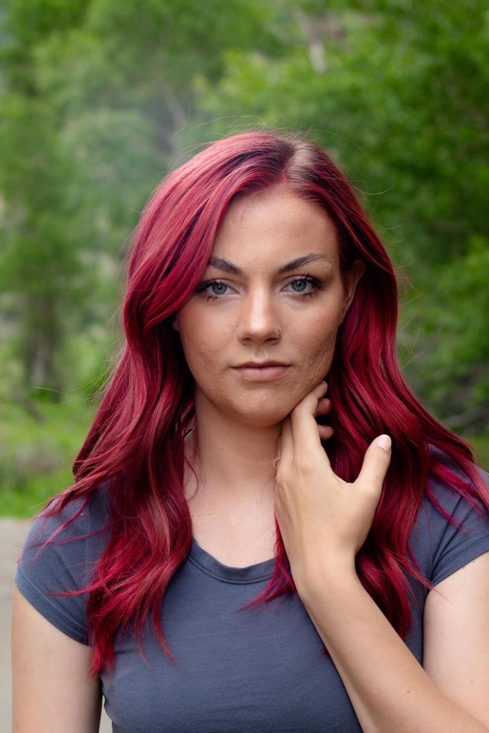 Free Image of A woman with vibrant red hair looks into the camera 