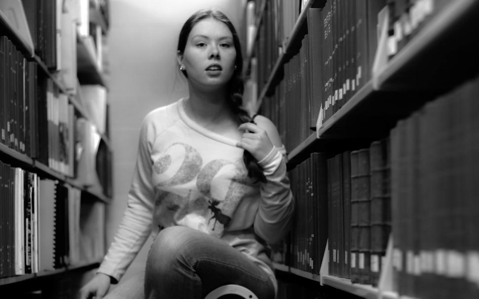 Free Image of Young woman with braid navigating library aisle 